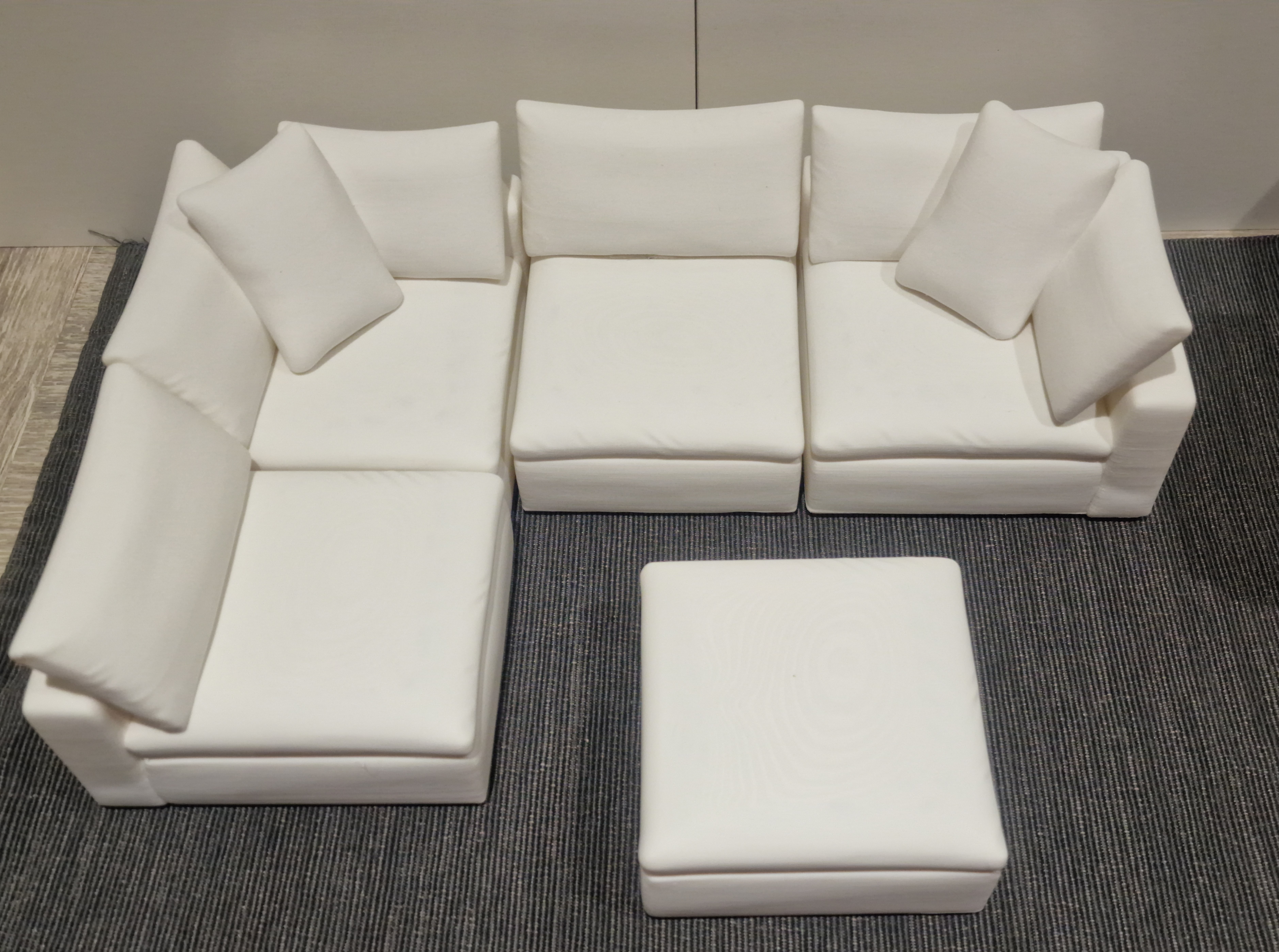 Five white miniature sofa modules arranged as an L-shaped sofa with a separate footstool.