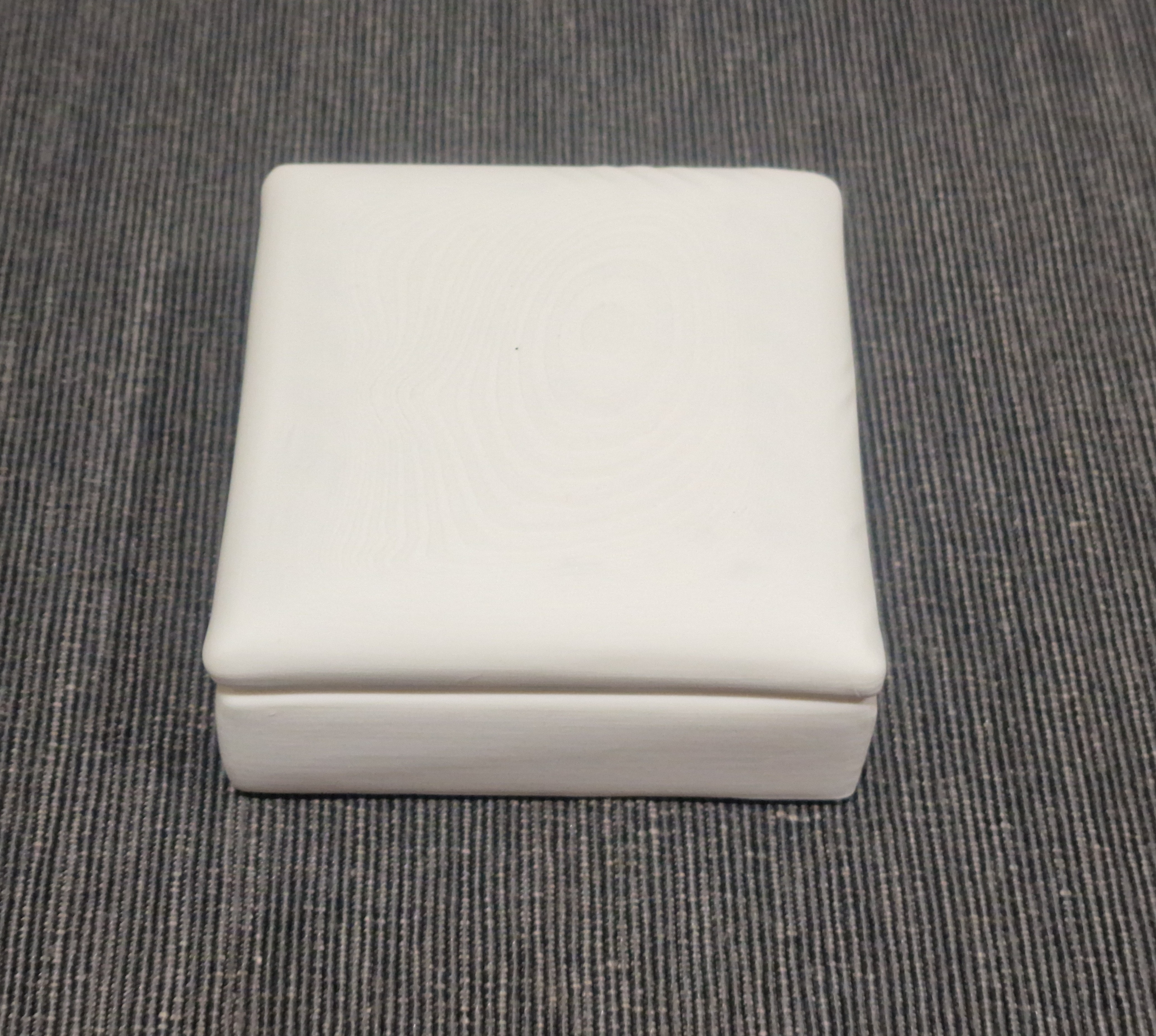 White 3D printed miniature footstool module with a square cushioned top and shaped edges.