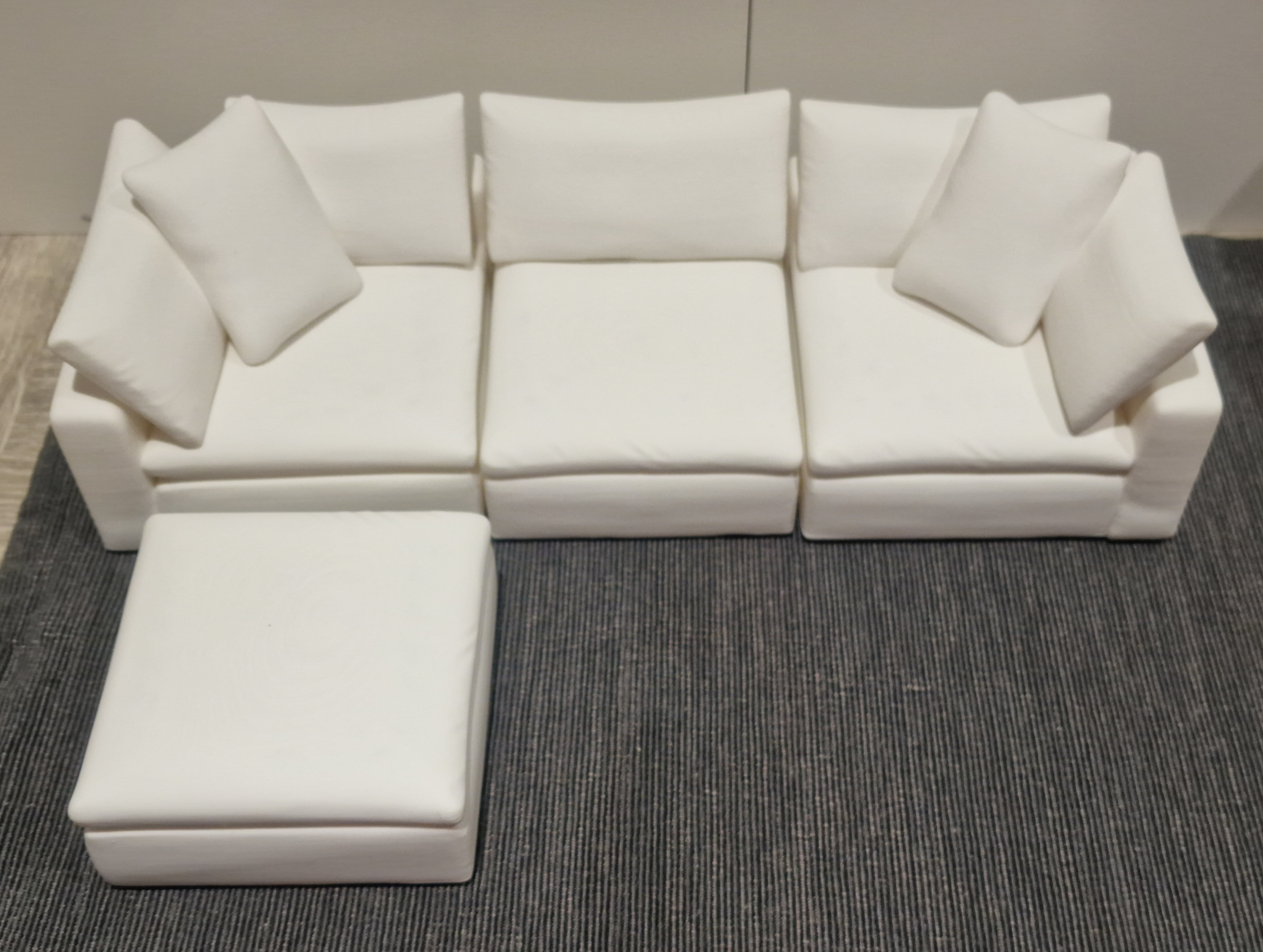 Four white miniature sofa modules arranged as a three-seat sofa with a footstool in front.